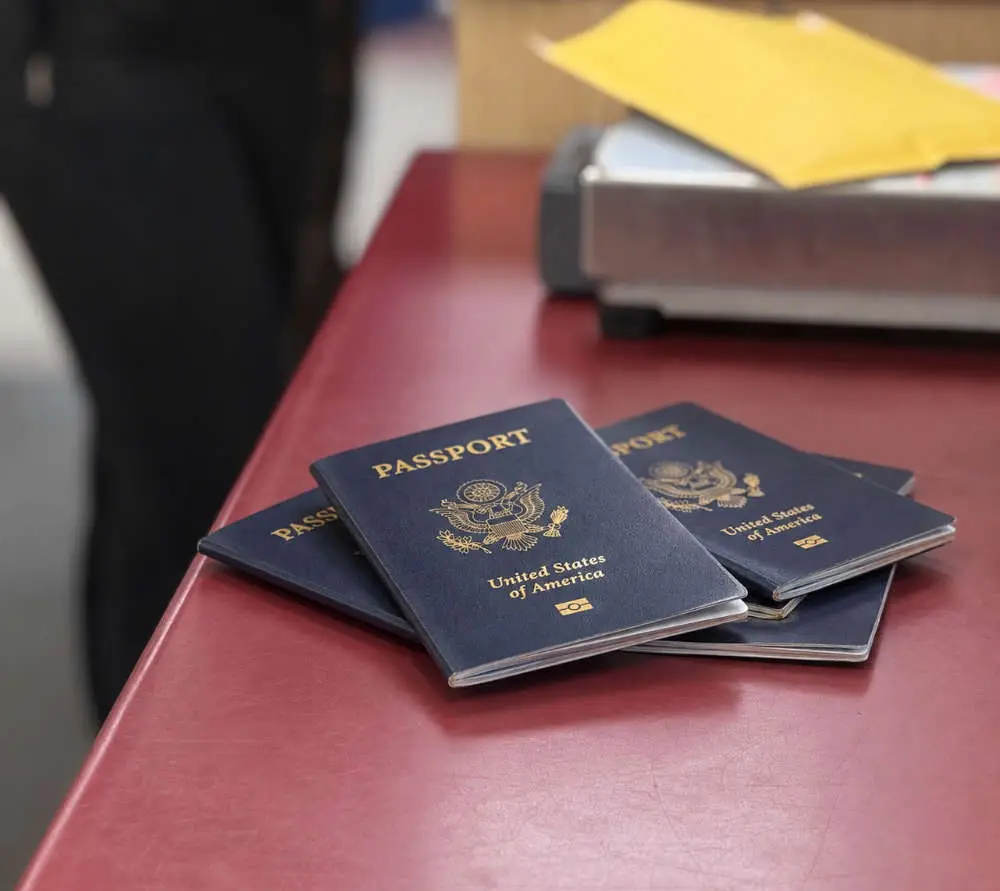 passport photos near me Four U.S. passports stacked on a red counter, highlighting the importance of passport photos in Bath, Maine.
